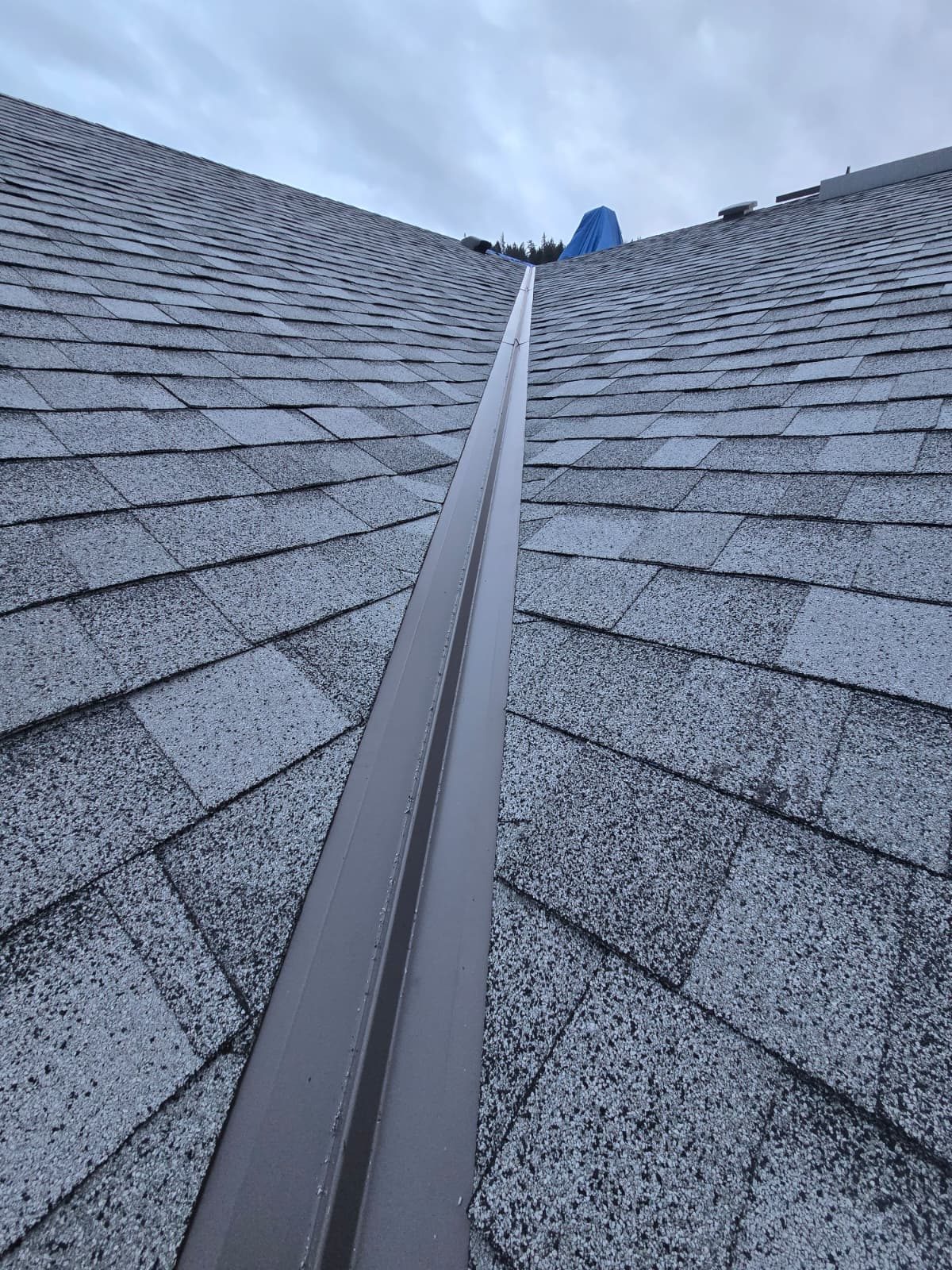 Finished grey shingle roof with a metal valley